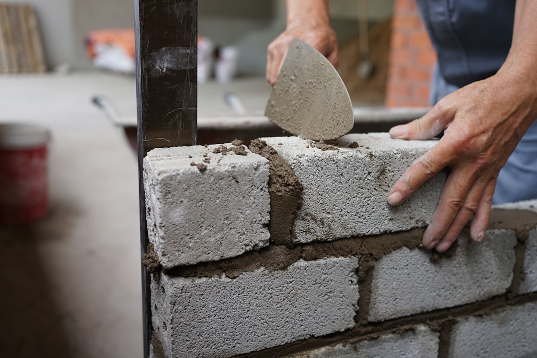 Builder laying blockwork with a trowel on site
