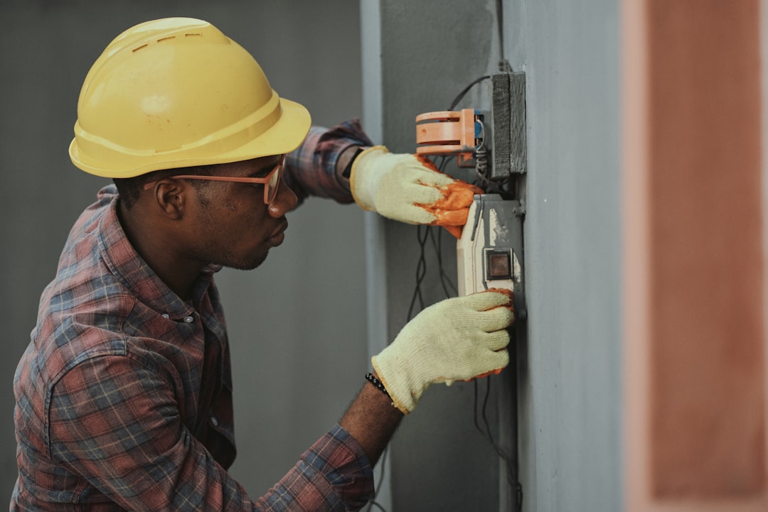 Electrician in a hard hat wiring an external unit
