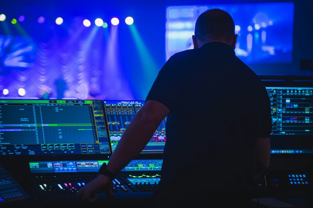 An AV technician running lighting and show control from the desk at a live event