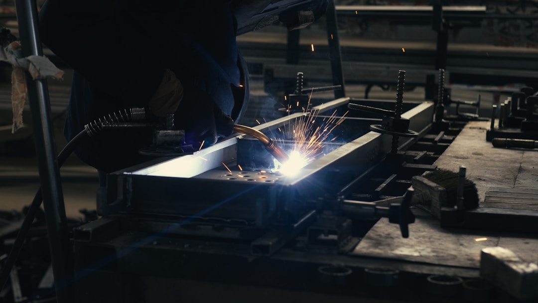 Welder fabricating a steel frame in a workshop